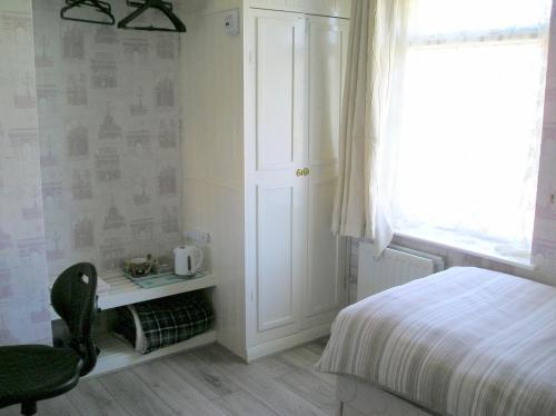 a bedroom with a bed and a chair and a window at Liverpool Airport Rooms in Speke