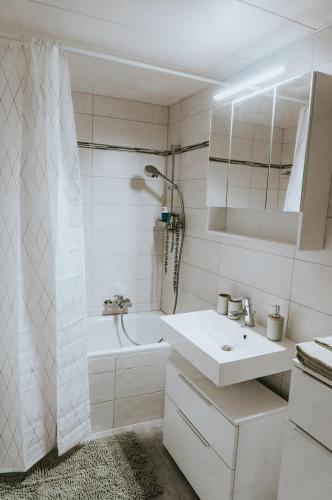 a white bathroom with a sink and a bath tub at The Nucleo House Experience in Maggia