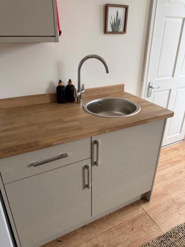 a kitchen sink with a wooden counter top at Glan Neigr Room 11 in Rhosneigr