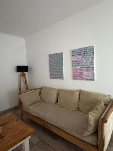 a living room with a couch and two paintings on the wall at SoHo Flat in Tandil