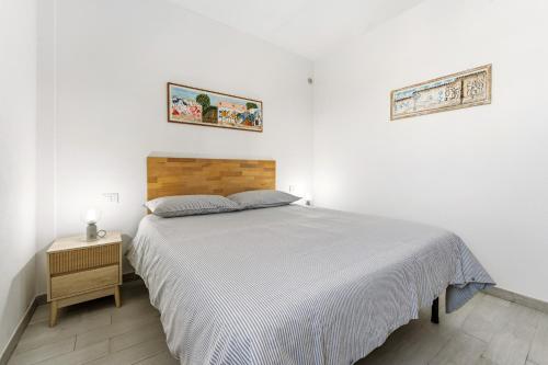 a white bedroom with a bed and a night stand at Casa Due Spighe in San Sperate