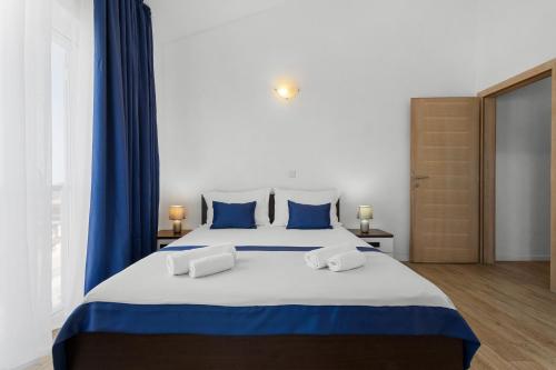 a bedroom with a large bed with blue curtains at Lotus Oliva Apart in Premantura