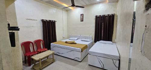 a room with two beds and two red chairs at Godavari Lodge in Solapur