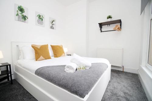 a white bed in a white room with gold pillows at Borough Street in Port Talbot