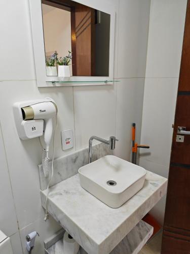 a bathroom with a white sink and a mirror at Suites Du'Mauro Terreo in Abraão