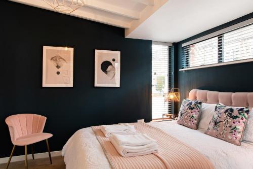 a bedroom with black walls and a bed with a pink chair at The Old Bakery in Norwich