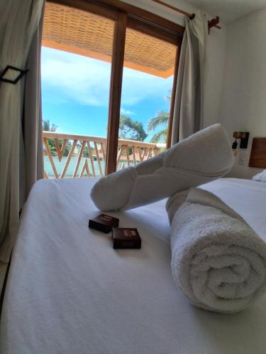a bedroom with a bed with a towel and a window at Casa Ilhéus Pousada in Ilhéus