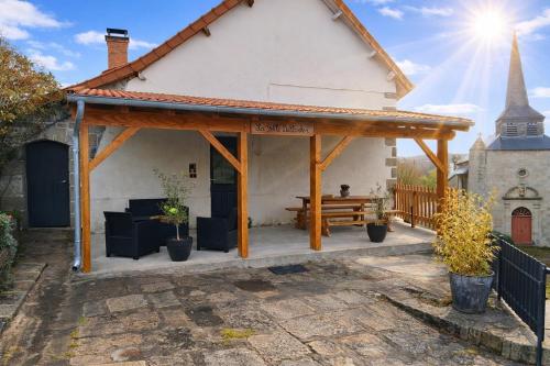 a wooden pavilion with a bench in front of a church at Gîte La Belle du Clocher in Saint-Pardoux-dʼArnet