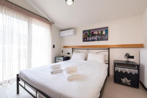 a bedroom with a large white bed with two towels on it at Aelion Airport Residence By SEM in Artemida