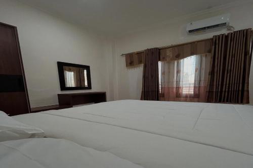 a bedroom with a white bed and a window at Mega Jaya Villa in Yogyakarta