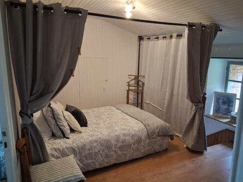 a bedroom with a bed with a canopy and a table at Gîte La Belle du Clocher in Saint-Pardoux-dʼArnet