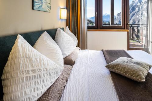 a bedroom with a bed with pillows and a window at Hotel Arcobaleno in Fai della Paganella