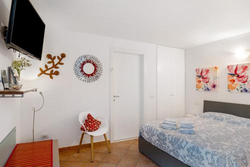 a bedroom with a bed and a chair and a television at Villa Benaco in Pozzolengo