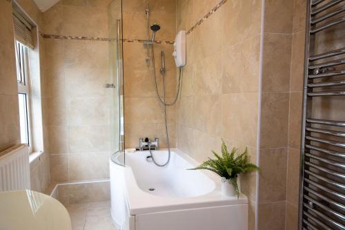 a bathroom with a shower and a tub and a sink at Ty Haf in Rhosneigr
