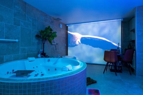 a bathroom with a bath tub with a bird flying at Sensori Nuit in Grand-Champ