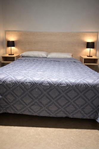 a large bed with two lamps on two tables at Rincón Sereno Tunuyán LODGE 1 in Tunuyán