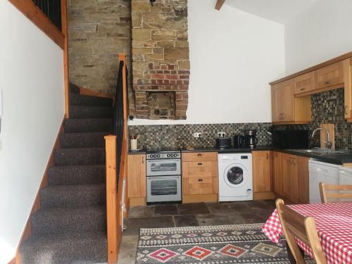 a kitchen with a staircase leading up to a kitchen with a stove at Edgerton cottage, large 1-bed detached coach house in town, Spacious rustic charm in Lindley