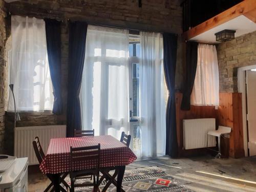a table and chairs in a room with windows at Edgerton cottage, large 1-bed detached coach house in town, Spacious rustic charm in Lindley