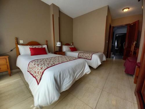 a hotel room with two beds with red pillows at Hotel Restaurante Oviedo in Luarca