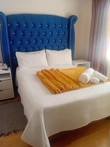 a bed with a blue headboard and white sheets and towels at Executive B & B in Beacon Bay