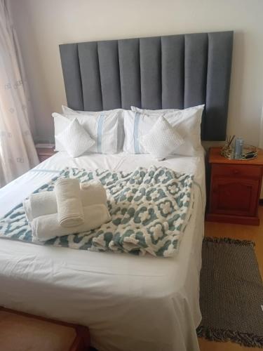 a bed with a blue and white blanket and pillows at Executive B & B in Beacon Bay