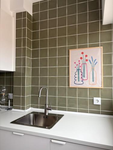 a kitchen with a sink and a picture on the wall at A Nossa Casa da Costa in Costa da Caparica