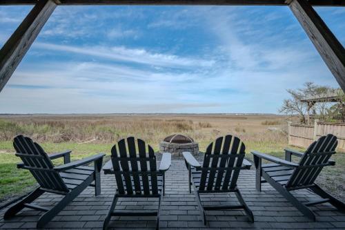 three chairs sitting on a porch looking out at a field at Late For The Sky in Caswell Beach