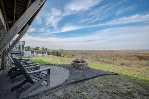 a patio with two chairs and a fire pit at Late For The Sky in Caswell Beach