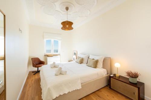 a white bedroom with a bed and a chair at Horizonte Azul - New Renovated with Sea View in Nazaré
