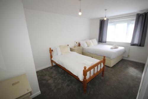 a bedroom with two beds and a window at Bath Road Place in Harmondsworth