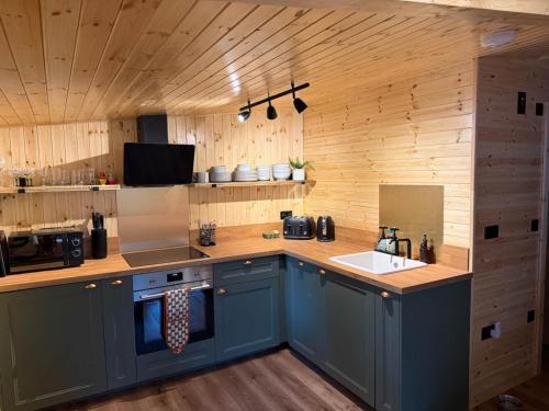 a kitchen with blue cabinets and a counter with a sink at Lake District Woodland Cabin - Close to Ambleside & Langdale Valley in Ambleside