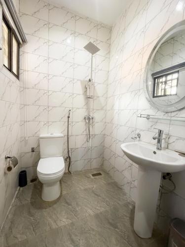 a white bathroom with a toilet and a sink at Macdestly Apartments in Abuja