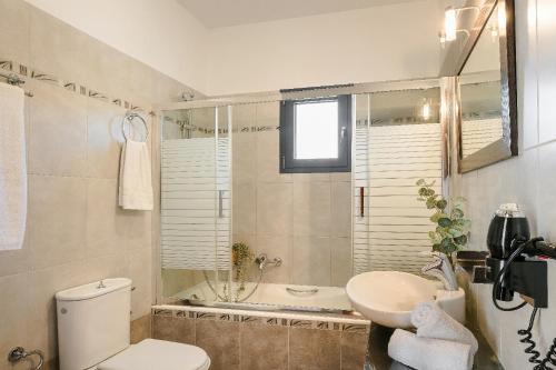 a bathroom with a toilet and a sink and a tub at Villa Xenia in Karavádhos