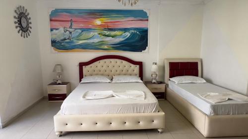 two beds in a bedroom with a painting on the wall at Villa Kliven in Durrës