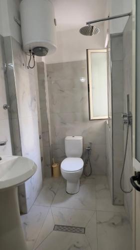 a white bathroom with a toilet and a sink at Villa Kliven in Durrës