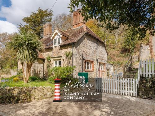 a house with a sign for the island holiday company at 1 Apse Castle Cottage - Chocolate Box Cottage, Pet-Friendly 16th Century Cottage, surrounded by Ancient Woodland in Shanklin in Shanklin
