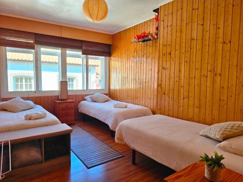 two beds in a room with wooden walls and windows at Real 43 Buen camino in Neda