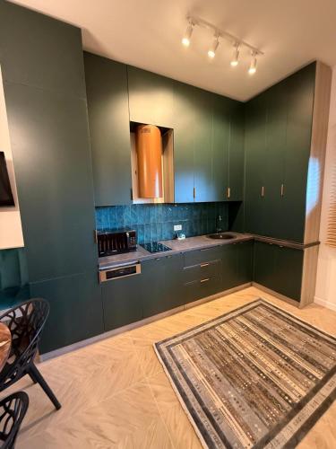 a kitchen with green cabinets and a rug on the floor at Tomis Villa Center Studio in Constanţa