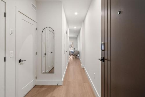 a hallway with white walls and a large mirror at Le Nomade Quartier Chinois in Montreal