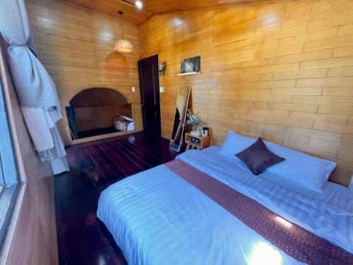 a bedroom with a bed and a wooden wall at tiny house in Ấp An Kroët