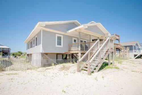 a house on the beach with a porch and stairs at Lowe Tide in Oak Island