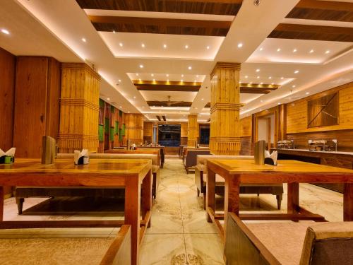 a dining room with wooden tables and chairs at Hotel Mistwood in Banikhet