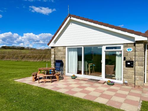 a small house with a patio and a table at BAYVIEW self-catering coastal bungalow in rural West Wight in Freshwater