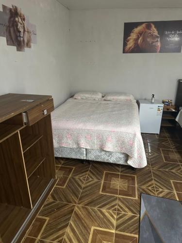 a bedroom with a bed and a wooden floor at Pousada Jangarelli in Guaíra