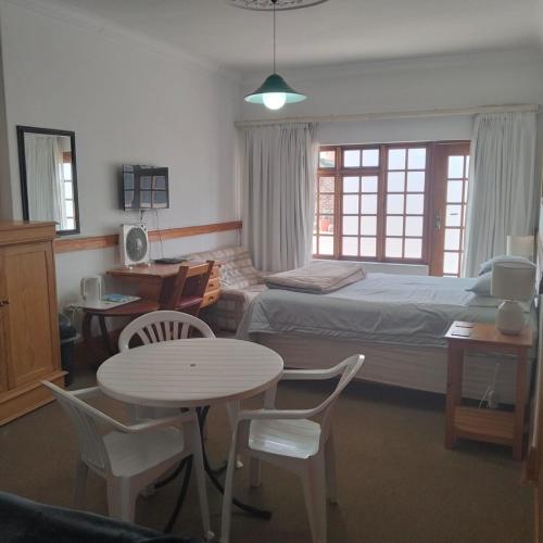 a bedroom with a bed and a table and chairs at Lekkerrus guesthouse in Krugersdorp