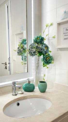 a bathroom sink with a vase with flowers in a mirror at Thelighthouse Porto Santo in Porto Santo
