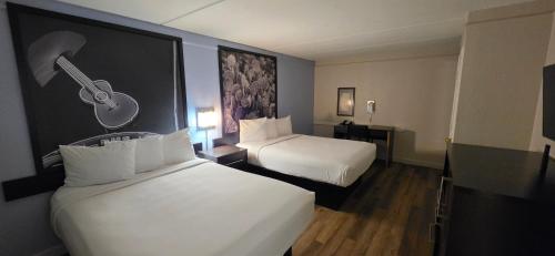 a hotel room with two beds and a guitar on the wall at Super 8 by Wyndham Austin South I-35 in Austin