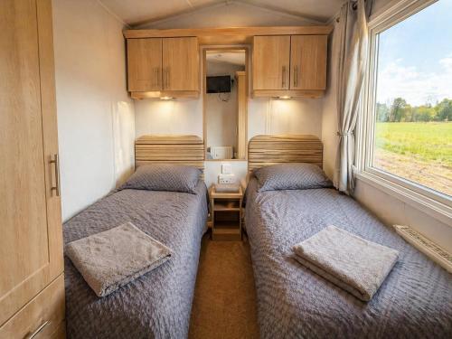 two beds in a small room with a window at FarmaKolonia2 in Zabiele