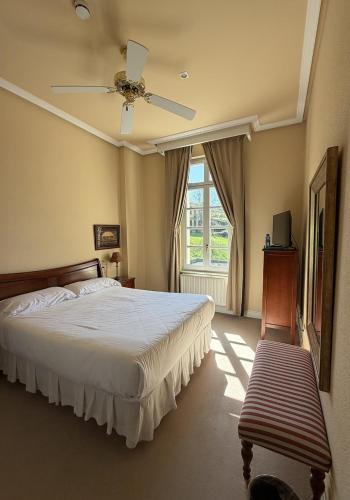 a bedroom with a bed with a ceiling fan and a window at Hotel Palacio de las Nieves in Langreo