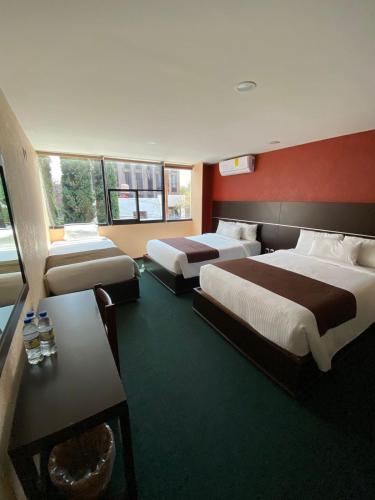 a hotel room with two beds and a table at Oaxaca Inn Reforma in Oaxaca City
